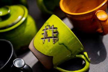 Green ceramic mugs close up with handmade artistic design of pagan symbols. Pottery kitchenware collection morning coffee cups vibrant tableware creative handcrafted drinkware