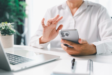 Close-up scene, a female seated at a table holds a smartphone, spending time on modern e-date...