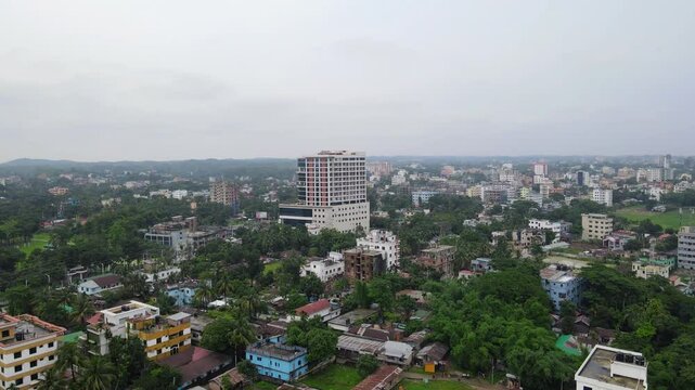 An aerial or elevated view of the cityscape of Sylhet, Bangladesh, featuring a mix of residential buildings, commercial structures.