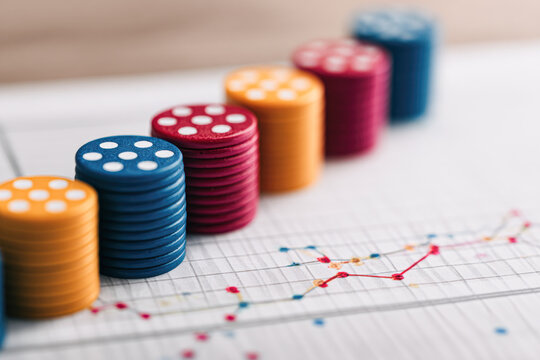 Stacks of colorful poker chips on a financial graph showing data trends and analysis. - Powered by Adobe
