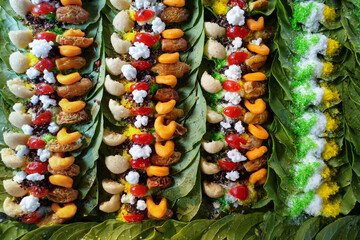 Close-up of colorful paan preparations on betel leaves, arranged in rows, showcasing various sweet treats and spices.