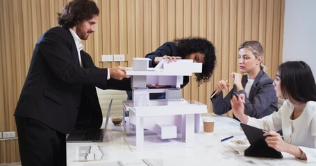 Confident female architect leads a meeting with colleagues in a design firm. Team listens attentively while reviewing a scale model and discussing creative ideas for a building project. - Powered by Adobe