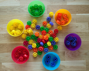 Ideas for educational games with children at home with various objects from everyday life. Using bottle caps from baby food to learn colors. 