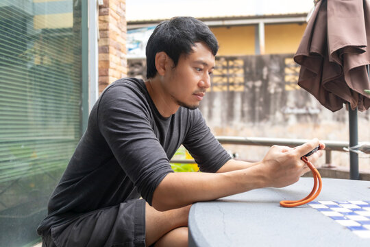 Asian man playing with small white dog on patio