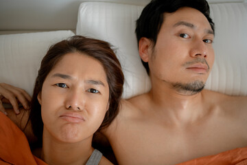 Playful Asian couple making funny faces in bed