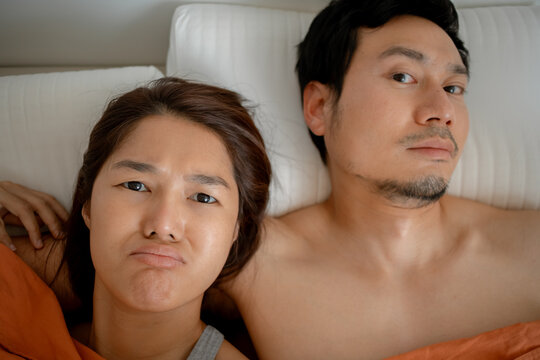 Playful Asian couple making funny faces in bed
