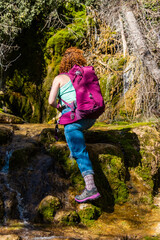 Hiker walking up mossy waterfall in forest