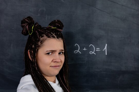 A confused student stands before an incorrect math equation on the chalkboard, puzzled