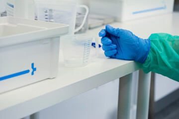 A healthcare professional's gloved hand rests on a clean medical laboratory table with measuring...