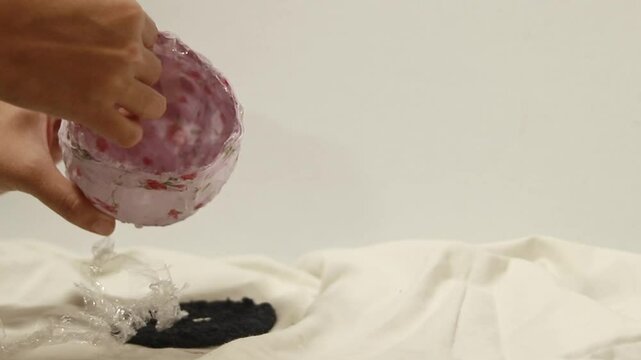 Showing and using the finished craft project made of cornstarch glue and recycled fabric to create a decoupage container