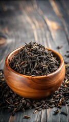 Fototapeta premium Dried black tea leaves in a wooden bowl