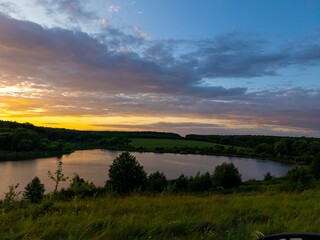 A view of a sunset over a lake in the middle of a grassy field