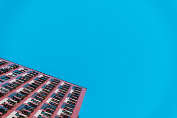 Fragment of a multi-storey modern residential building against the blue sky. View from below.