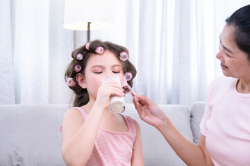 Kids, cosmetic, child, beauty, makeup, A girl with hair curlers drinks dairy from a glass while her...