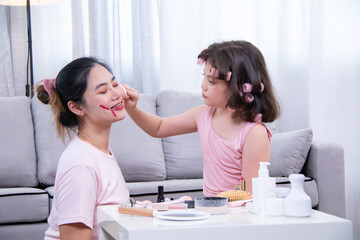 Fototapeta premium Kids, cosmetic, child, beauty, girl, A cheerful moment between Asian mother and mixed daughter as they playfully apply makeup together, expressing love, laughter, and family connection at home