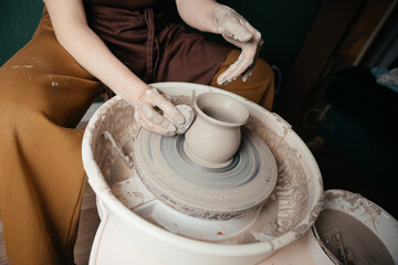 Potter shaping a ceramic artwork on a wheel. Hands in clay. Artistic pottery workshop