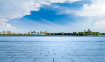 Empty square floor and city skyline with a beautiful park by the lake under blue sky