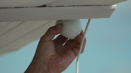 Hand Pull Blind operating cord under white structure against blue sky