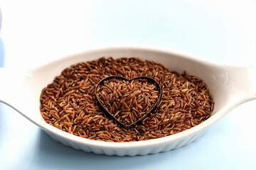 Heart-shaped on healthy uncooked raw red rice.