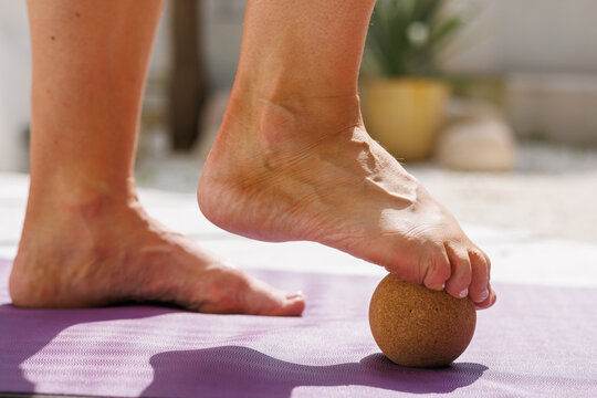 Foot Using Cork Massage Ball for Plantar Fasciitis Relief and Wellness on Yoga Mat Close Up