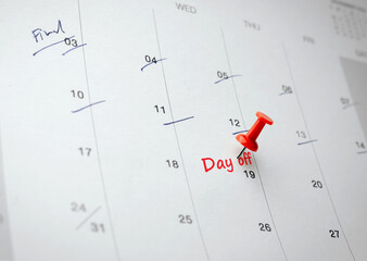 A red pin placed on 19th day of month with written word Day off on white calendar. Concept of Work...