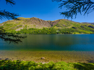 Tranquil lakeshore with clear water and green mountains (Buttermere, Lake District, England, United Kingdom)