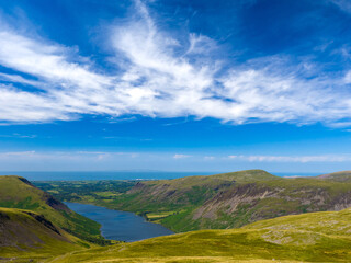 View from Scafell Pike overlooking Wast Water and the Isle of Man on the horizon under the summer sky with cirrus clouds (Lake District, England, United Kingdom)