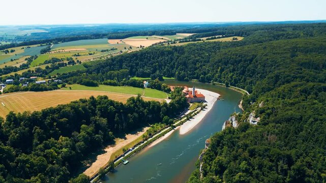 Kloster Weltenburg on the Danube River, Germany, shot from a drone in summer. Historic Benedictine monastery surrounded by forested cliffs and dramatic river curves near Kelheim