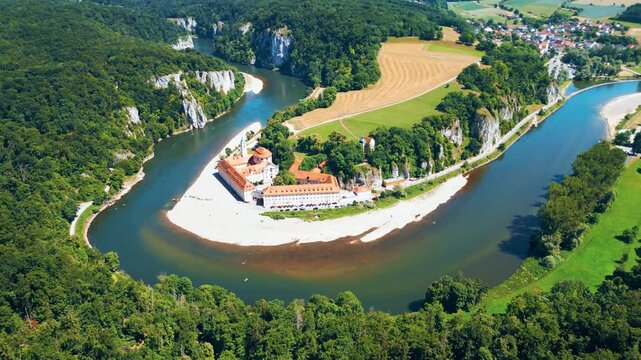 Kloster Weltenburg on the Danube River, Germany, shot from a drone in summer. Historic Benedictine monastery surrounded by forested cliffs and dramatic river curves near Kelheim