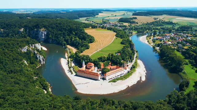 Kloster Weltenburg on the Danube River, Germany, shot from a drone in summer. Historic Benedictine monastery surrounded by forested cliffs and dramatic river curves near Kelheim