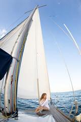 Beautiful young girl in a white shirt at sea on a yacht in summer