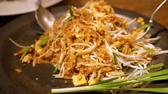 Close up to a plate of thai traditional food, Shrimp Pad Thai, dry noodle street food in Thai food style while stiring in plate ready to eat