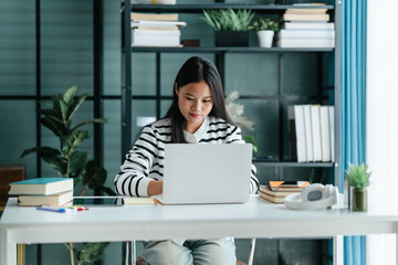 Female Asian student using laptop for online learning at home