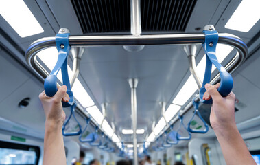 People hand holding handle on subway