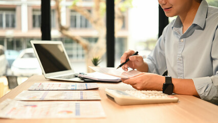 Close-up of hands holding financial papers and pen, working on business strategy and budgeting in a...