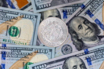 Silver coin 1 US dollar on a background of US paper banknotes. Ounce of silver