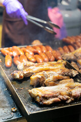 Juicy slices of grilled wild boar meat being roasted over open flames at a night market food stall. The smoky aroma and charred edges highlight the rustic and flavorful appeal of traditional street cu