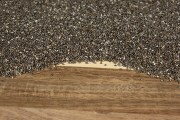 Pile of raw chia seeds on wooden background, natural superfood, space for text.