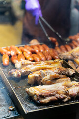 Juicy slices of grilled wild boar meat being roasted over open flames at a night market food stall. The smoky aroma and charred edges highlight the rustic and flavorful appeal of traditional street cu