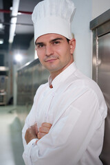 Portrait of Professional male chef in white uniform and hat with arms crossed and looking camera,...