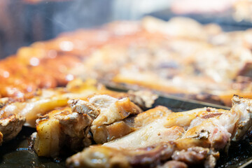 Juicy slices of grilled wild boar meat being roasted over open flames at a night market food stall....