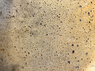 The concrete surface displays a detailed texture filled with dark holes and small imperfections.