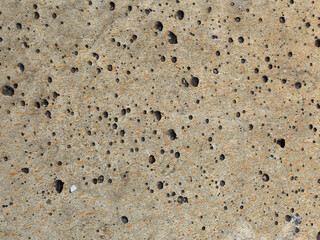 Detailed concrete surface texture featuring small holes and a weathered appearance.