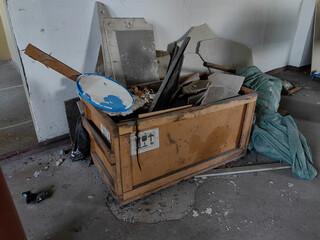 A wooden crate filled with construction debris sits on a weathered concrete floor.