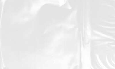 plastic transparent cellophane bag on white background. The texture looks blank and shiny. The plastic surface is wrinkly and tattered making abstract pattern