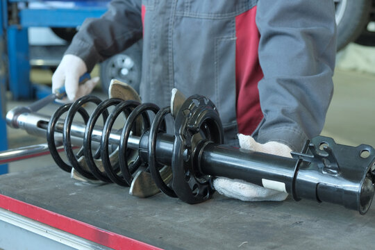 Car maintenance at a car service center. An auto mechanic performs car suspension repairs.Preparing the shock strut for replacement on the car.