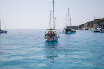 abstract blur sailboats on clear blue Ionian Sea with rocky coastline in distance