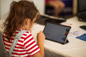 Little girl drawing on digital tablet using a digitized pen. Children's engagement of digital...