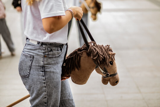 Young woman hobby horse riders jumping with stick toy horse