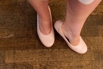 Dancer practices grace and poise in soft ballet shoes on warm wooden floor during a twilight rehearsal